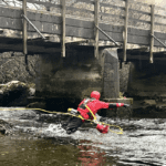 A rescuer performing a live-bait rescue in flowing water. All part of the event water rescue & water safety cover North West Medical Solutions provides.